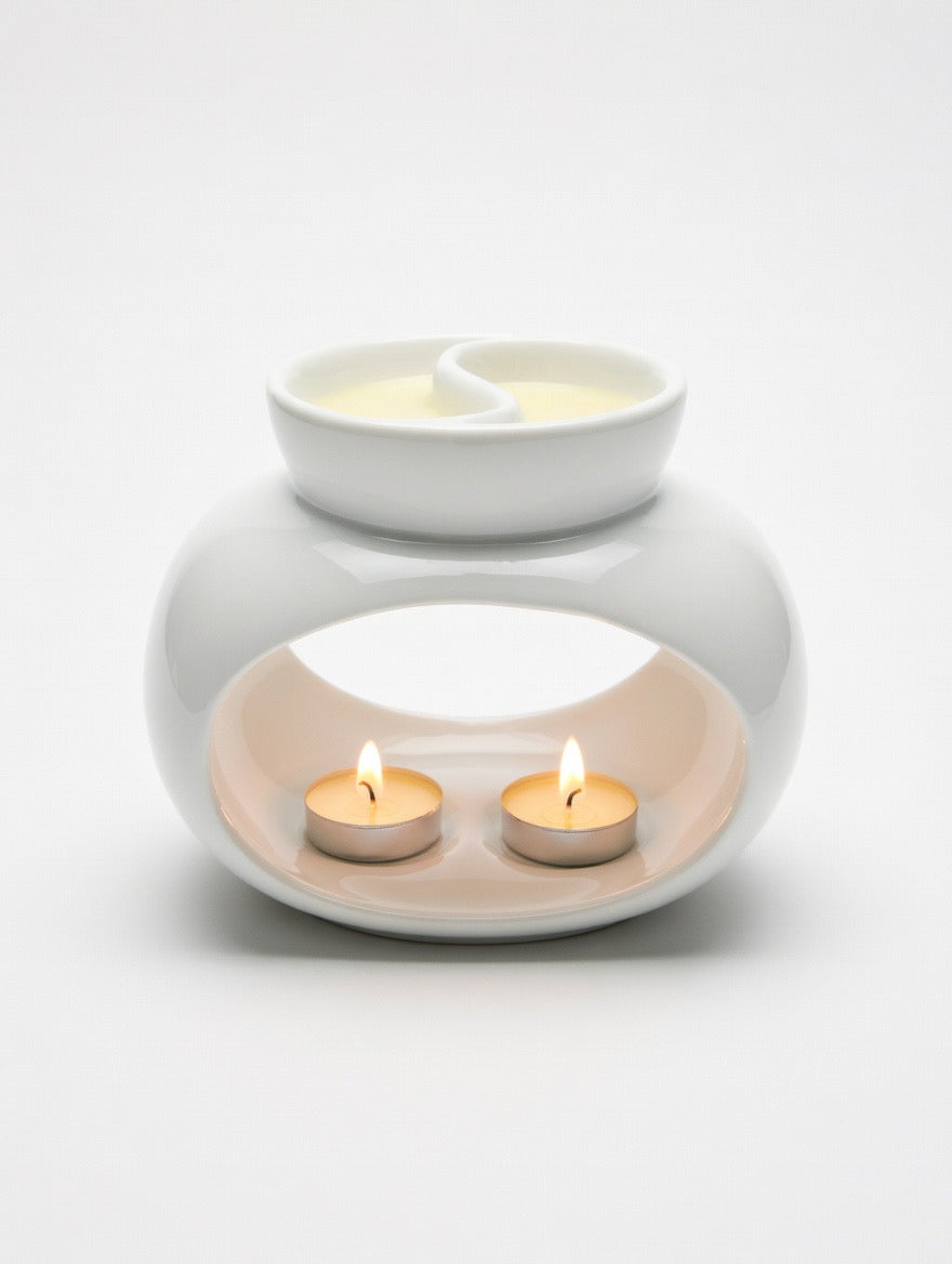 White ceramic oil burner with two lit tealights on a white background